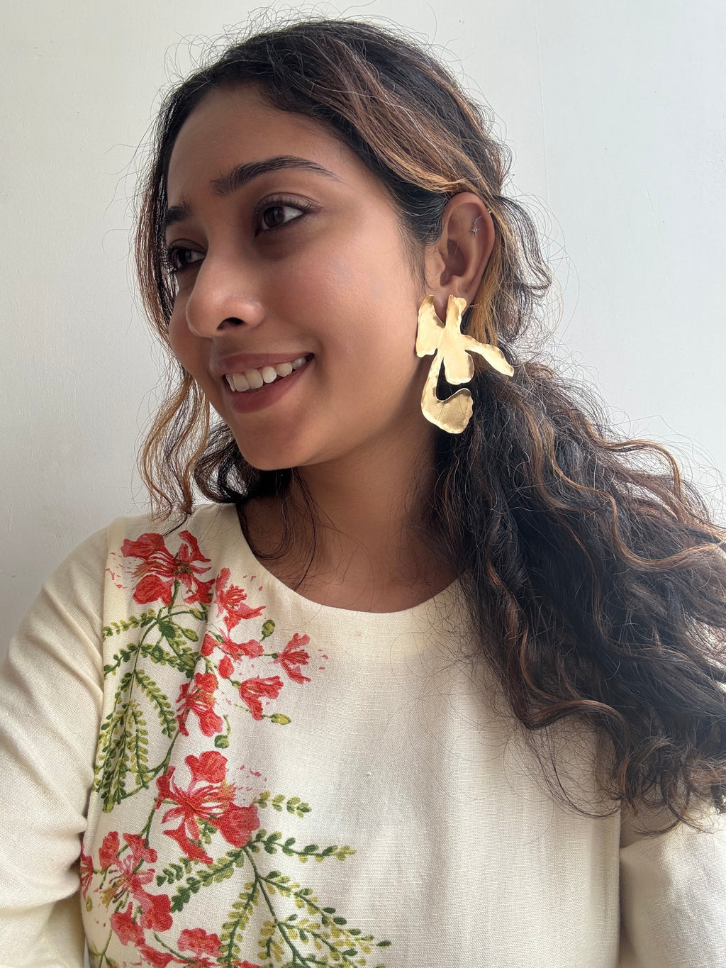 Woman wearing Ankur Twist Earrings with a floral-patterned top against a plain background