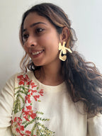 Woman wearing Ankur Twist Earrings with a floral-patterned top against a plain background