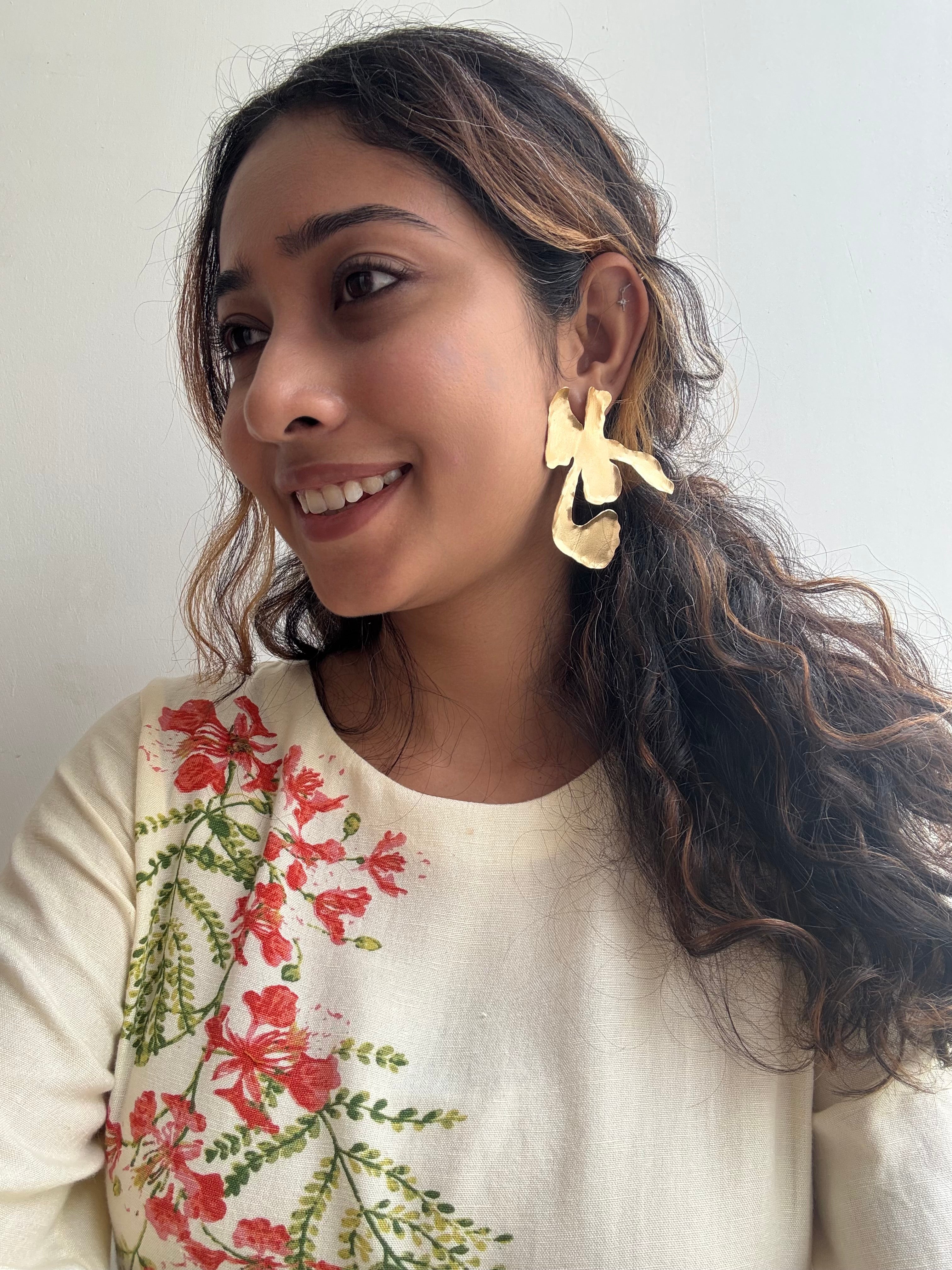 Woman wearing Ankur Twist Earrings with a floral-patterned top against a plain background