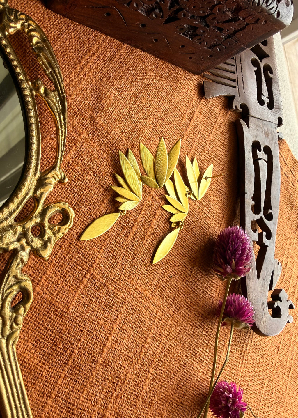 Front and Back view of Overhead flatlay of Apsara danglers on terracotta linen with antique hand mirror, wooden carved box, and dried purple flowers, warm natural light