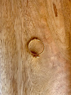 Close-up of the Bandhani Ring lying on a textured wooden surface, top view.