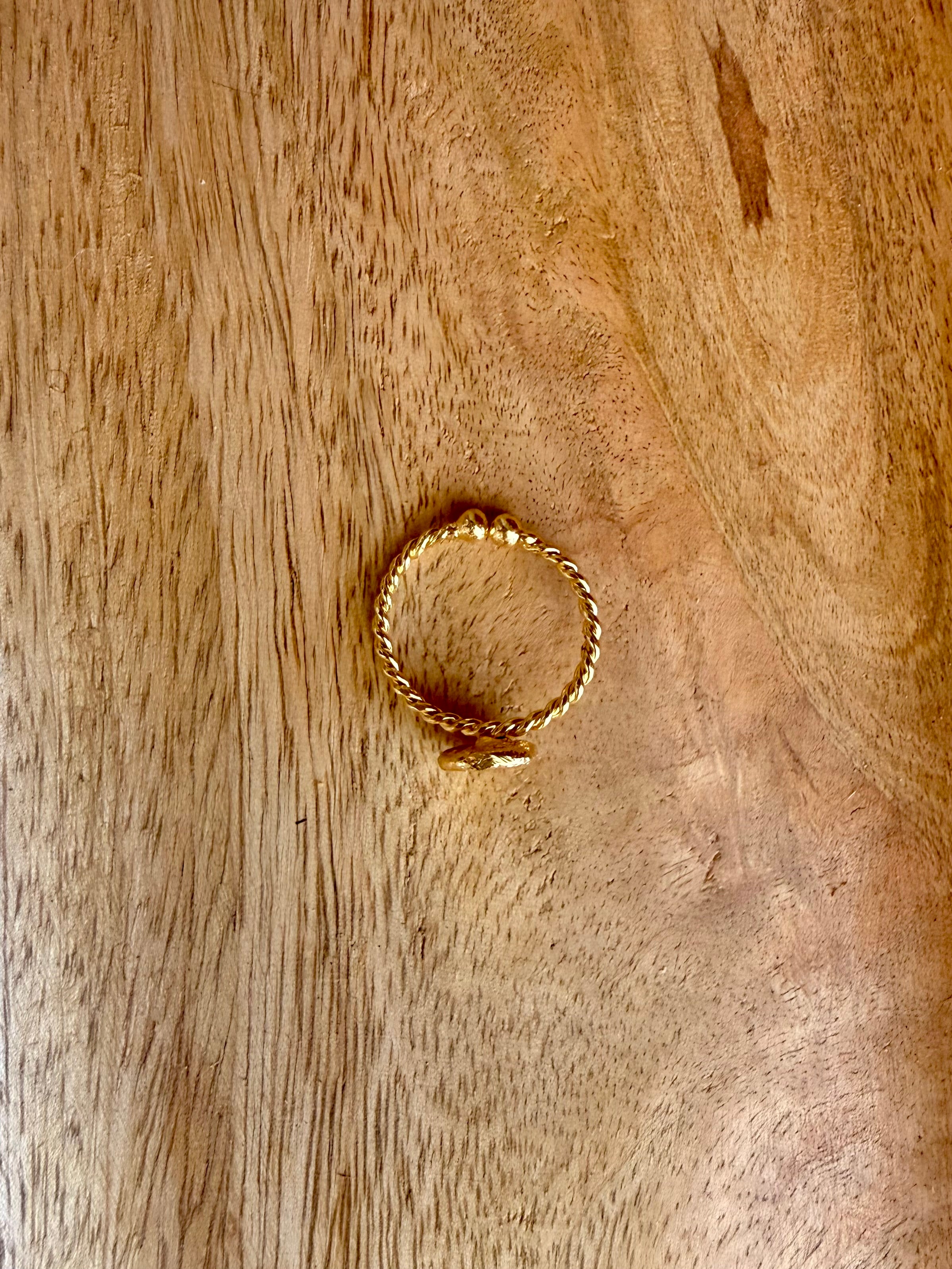 Close-up of the Bandhani Ring lying on a textured wooden surface, top view.