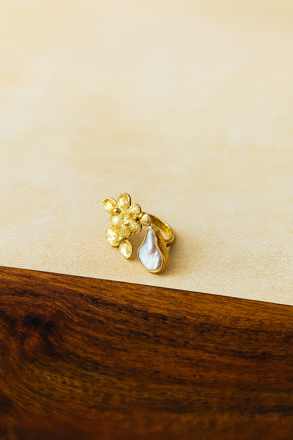 Gold plated ring with floral design on a wooden surface.