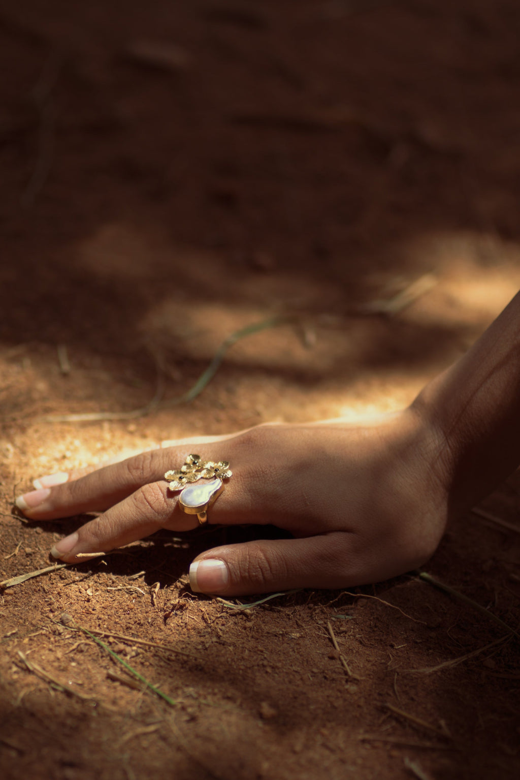 Hand with a ring on a sandy surface