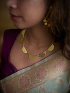Woman wearing a gold colored necklace and earrings with a floral saree