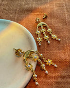 Gold earrings with pearl accents on a textured surface