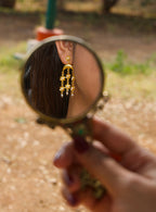 Gold earring visible on a vitage hand mirror.
