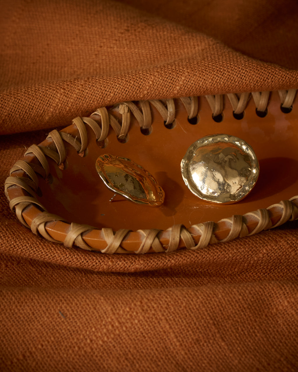 Close up of chunky gold plated textured round stud earrings kept on a terracotta tray.