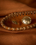 Close up of chunky gold plated textured round stud earrings kept on a terracotta tray.