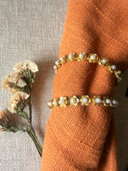 Close up of gulnaar hoops displayed on an orange fabric napkin over a gray textured surface with dried flowers.