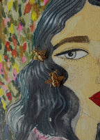 Close-up of a painting having woman's face with bee earrings against a floral background.