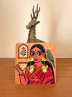 Juhi earrings on a illustrative earring card having a woman drinking tea, parrot on one shoulder.