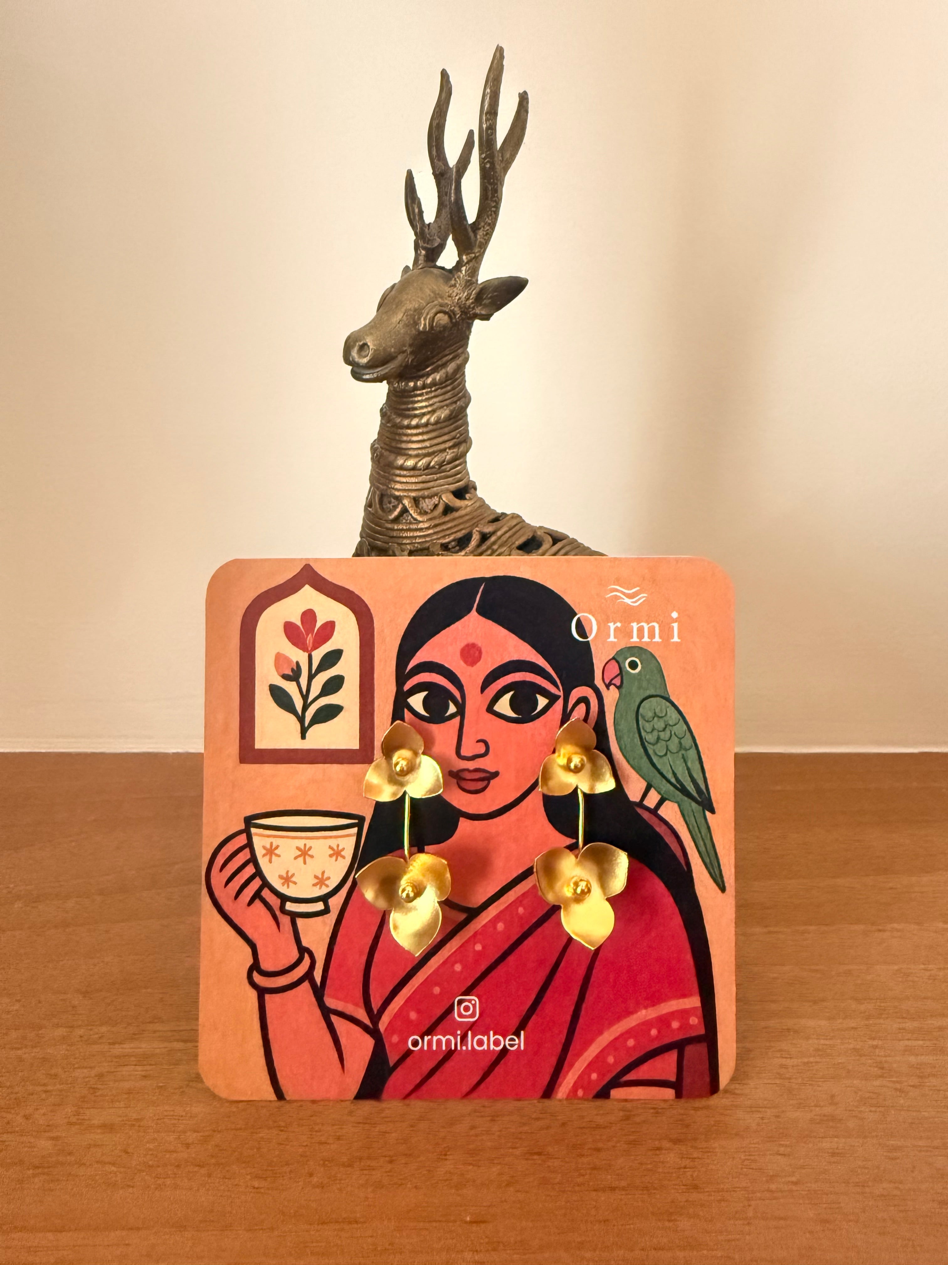 Juhi earrings on a illustrative earring card having a woman drinking tea, parrot on one shoulder.