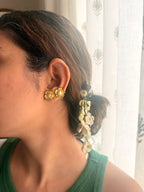 Close-up of a woman in green top, wearing Champafloral earrings with floral crochet hair accessory a blurred background