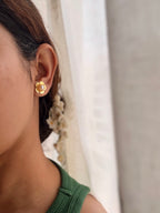 Close-up of a person wearing champa floral earrings with a blurred background