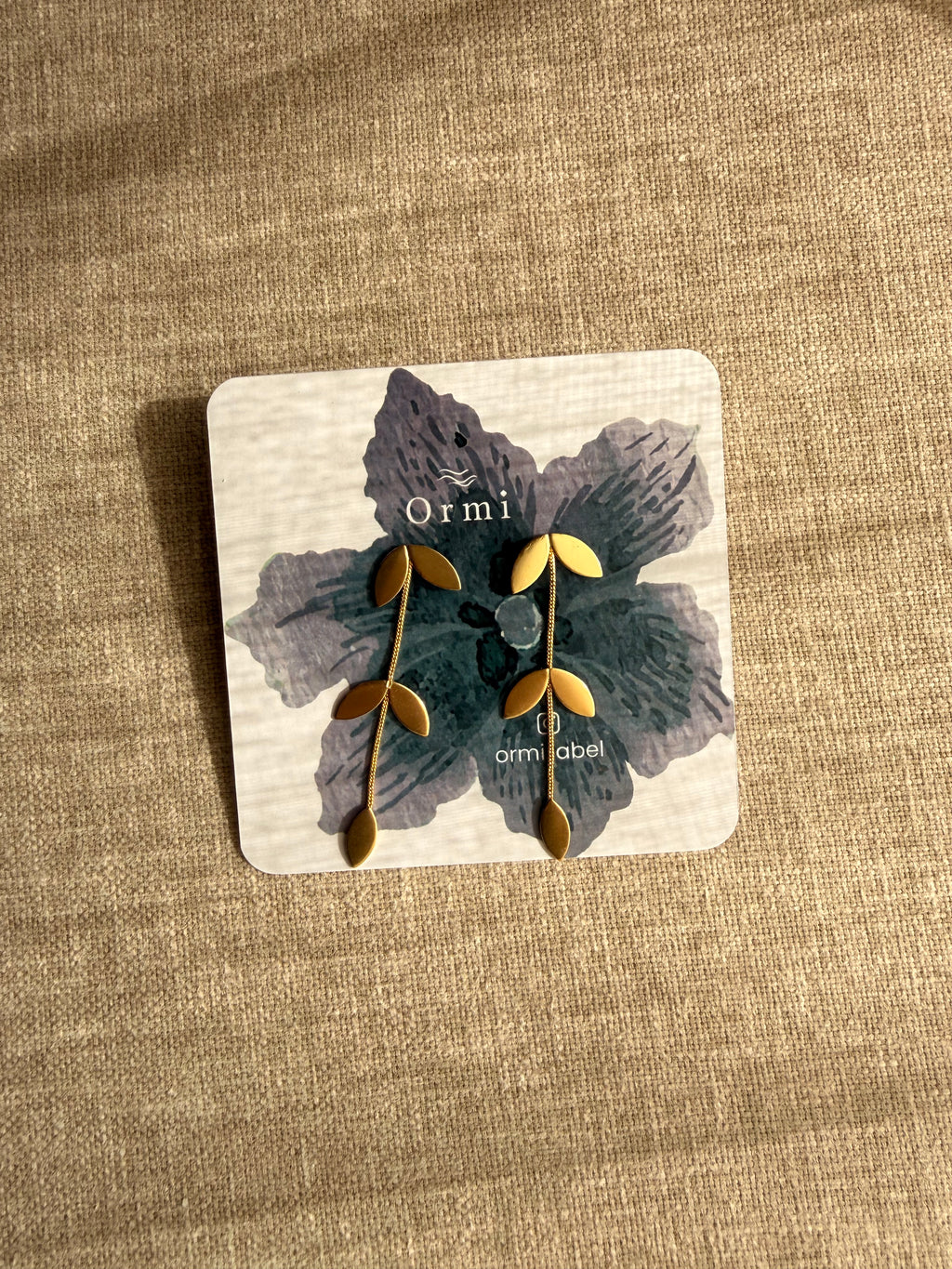 Pallavi earrings on a Ormi branded card with a textured beige background