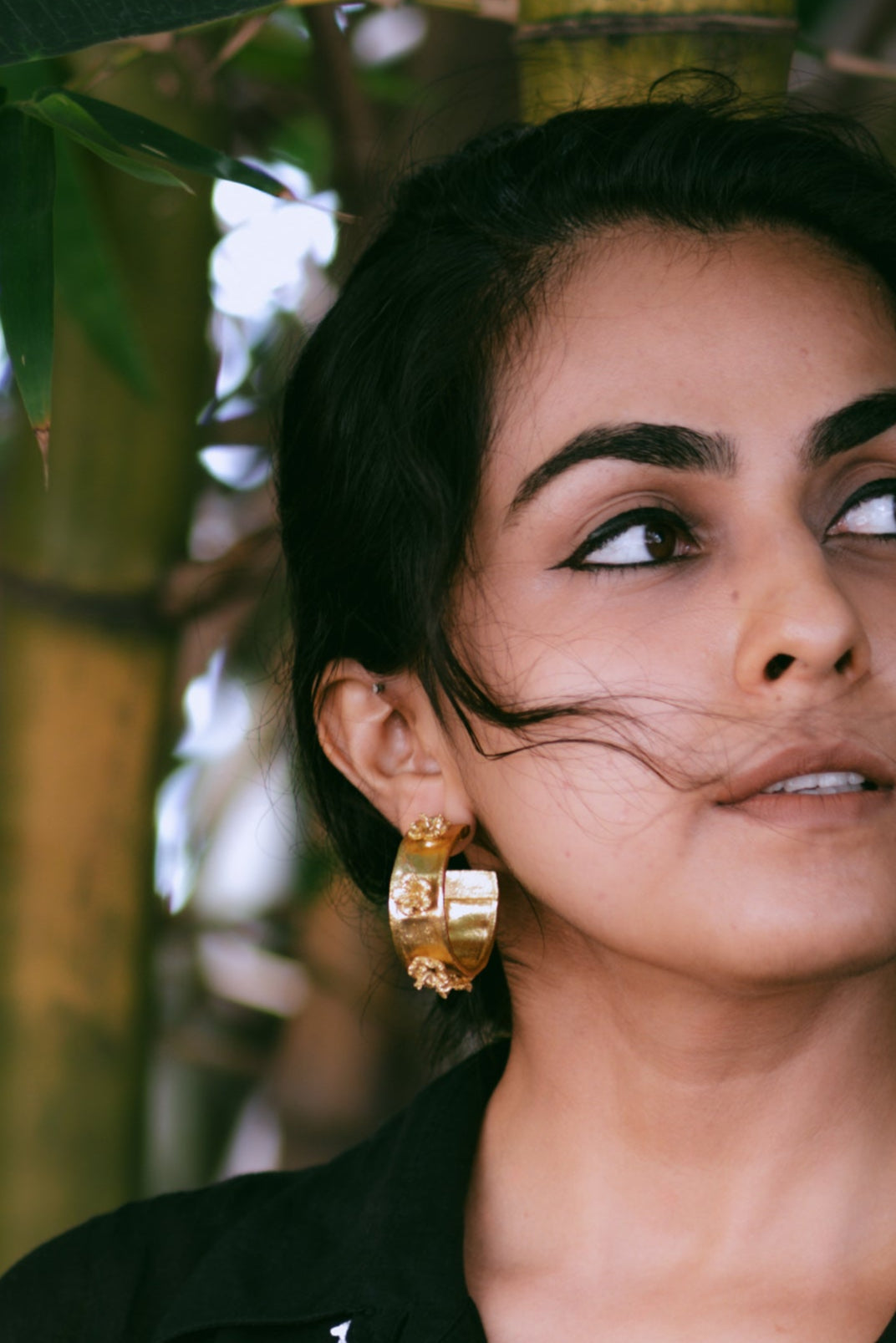 Closeup of a woman with wavy hair, wearing Japa Pushpa Hoops.