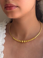 Close-up of a person wearing a gold necklace with a neutral background