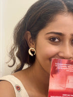 Woman wearing a gold earring holding a red book