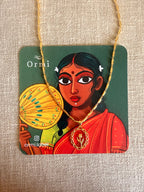 Lily Necklace draped over an Ormi branded packaging card featuring a traditional Indian woman illustration in a red saree, placed on natural linen texture.