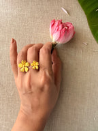 A model wearing the gold Manjari Ring on her index finger while delicately holding a pink lotus bud.