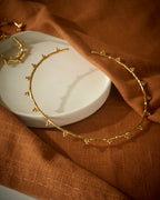 Gold circular chocker on a white dish with a brown fabric background
