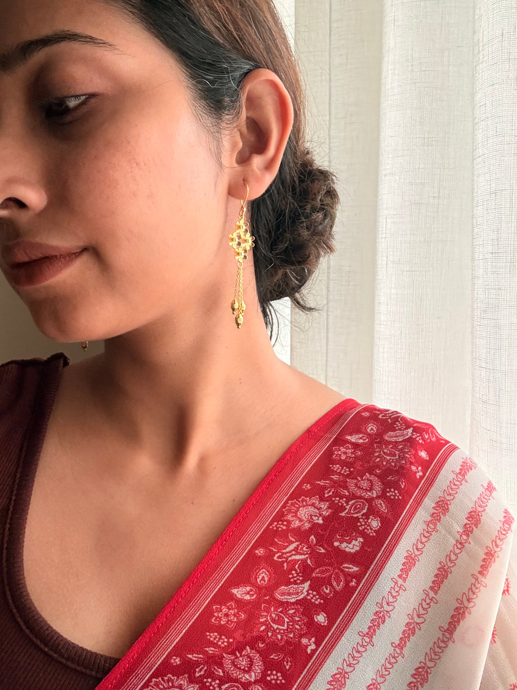 Motiya Danglers worn on the ear — jasmine flower cluster with delicate hanging chains and gold beads, styled with hair in a loose bun and a red printed dupatta, photographed from side angle in soft natural light.