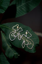 Naksh Floral Earrings on a green leaf with a dark background