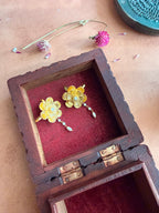Nargis Ear Cuffs nestled inside an antique wooden box with red velvet lining, gold flower and pearl drop visible, dried flowers and petals on terracotta surface around it