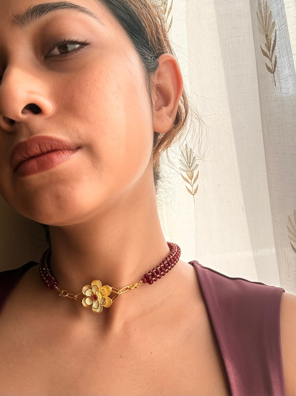 Close-up of a woman in a mauve blouse wearing the Nargis Mala necklace in soft natural light.