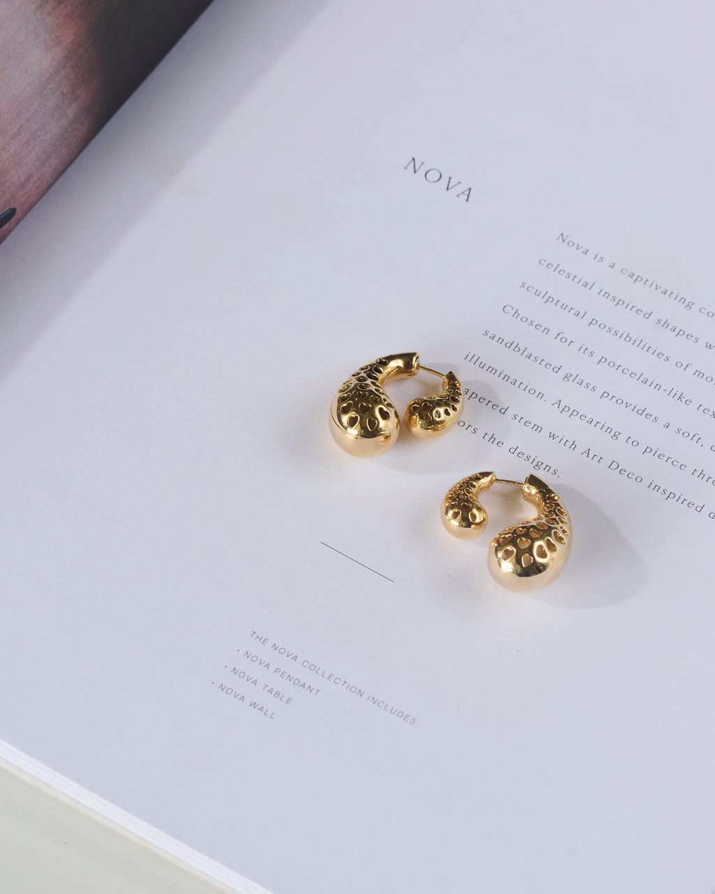 Paisley shaped gold plated double sided stud earrings kept on a book.