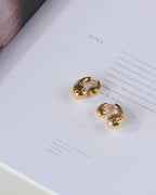 Paisley shaped gold plated double sided stud earrings kept on a book.