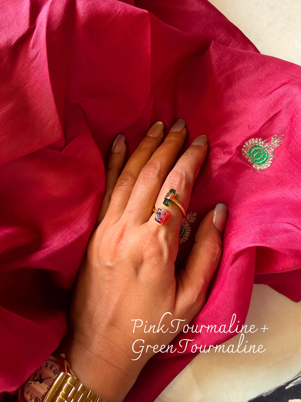 Pink Tourmaline and Green Tourmaline ring with two small stones set side by side, worn on a hand resting on pink silk