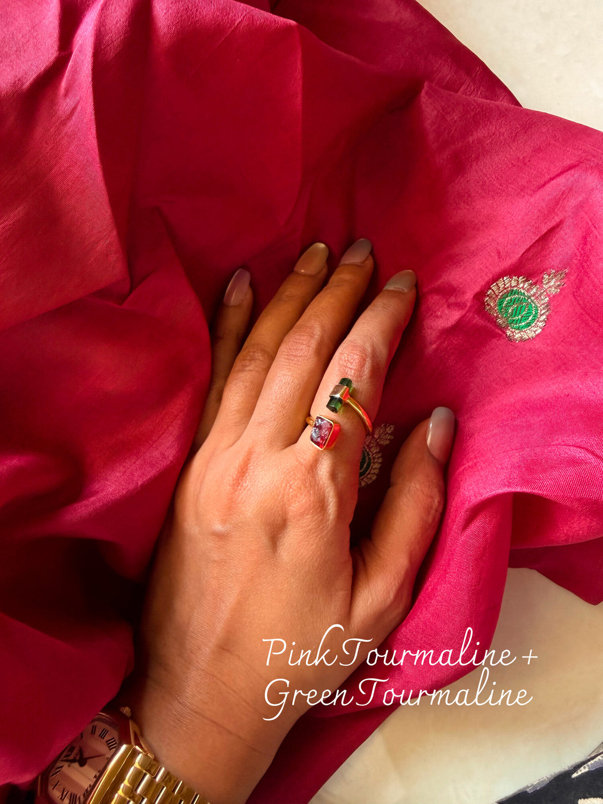Pink Tourmaline and Green Tourmaline ring with two small stones set side by side, worn on a hand resting on pink silk