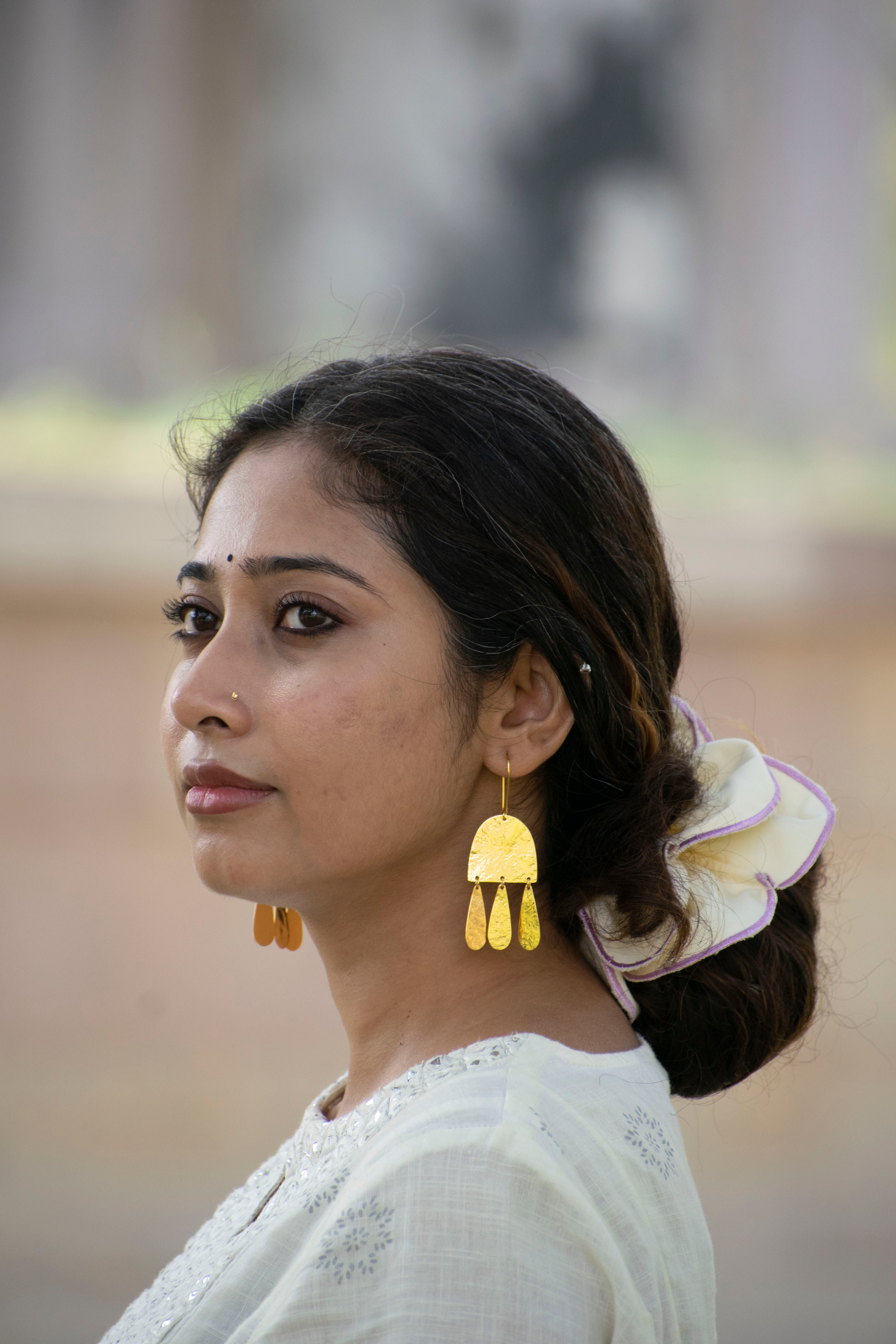 Woman wearing gold earrings with a blurred background