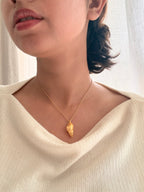 A close-up lifestyle shot of a woman wearing a delicate gold chain Sagarika necklace, paired with a cream-colored ribbed knit top.
