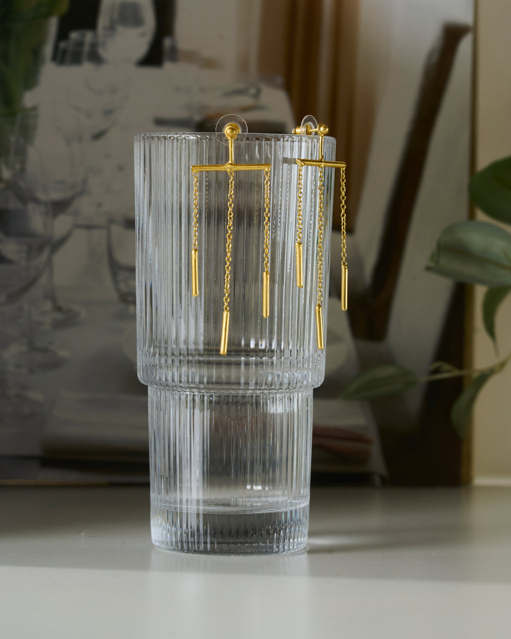 Fluted glass vase with gold toned chain dangling earrings.