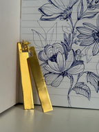 Gold plated geometric dangler ear studs on a notebook with hand drawn floral design.