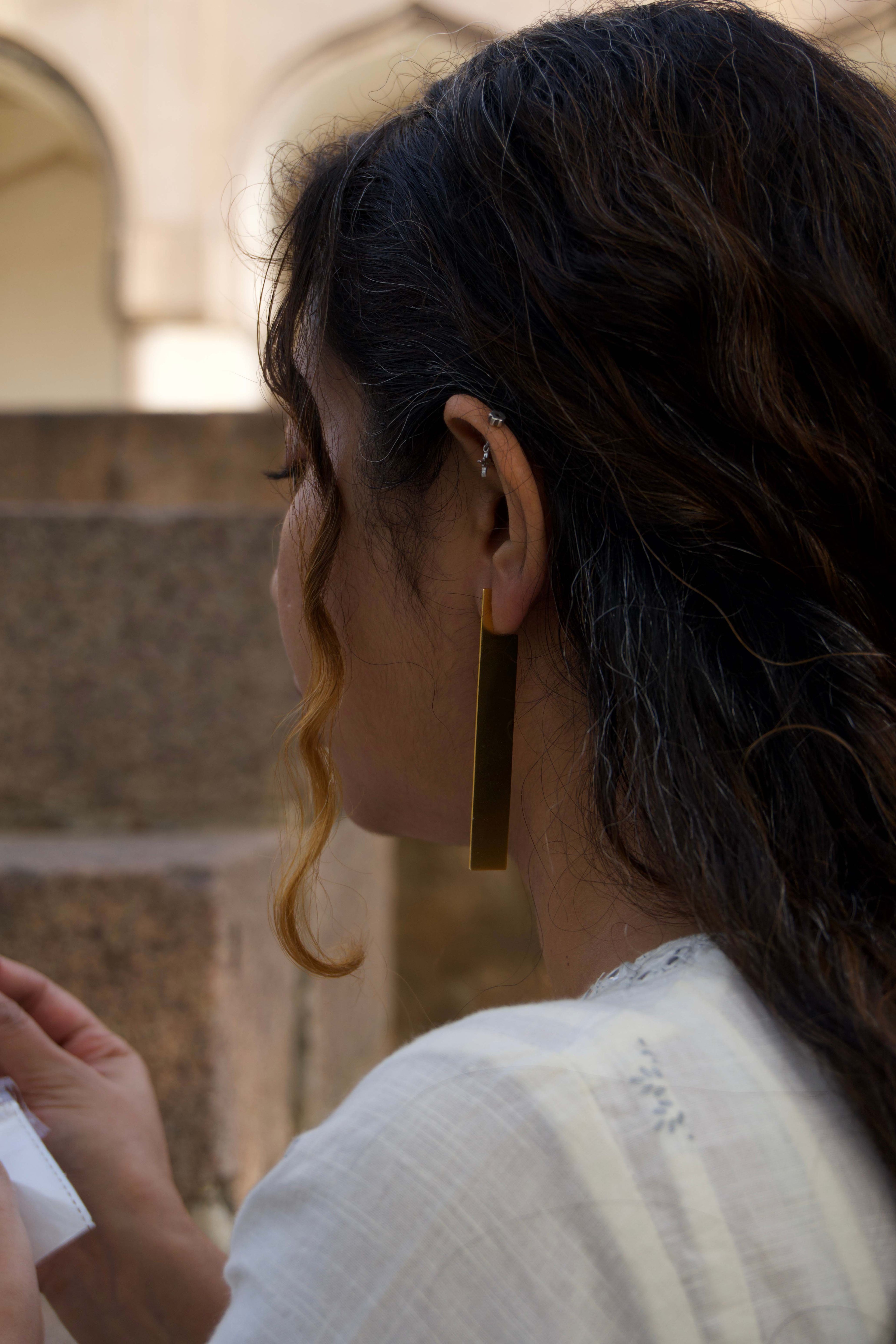 Close-up of a person wearing a gold earring with a blurred background