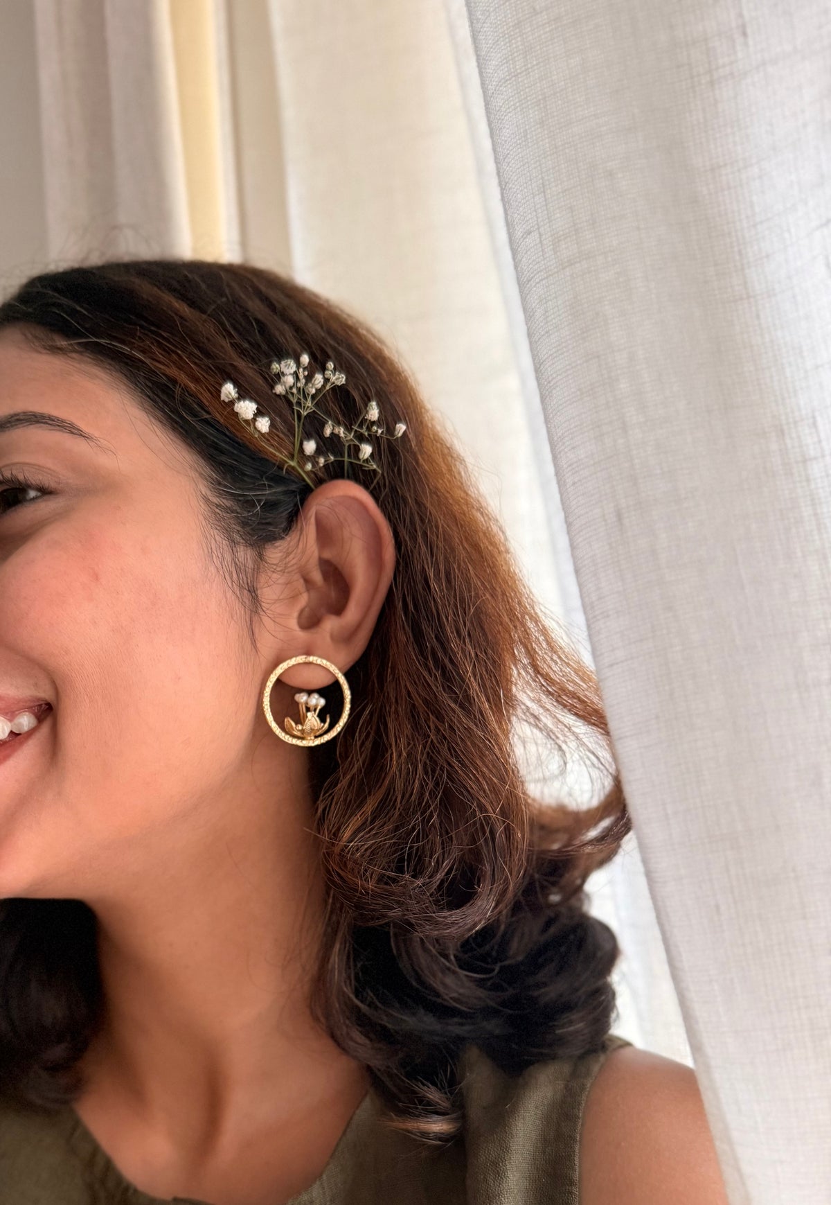 ide profile of a smiling woman wearing the gold Tagar Studs, styled with soft curls and baby's breath flowers in her hair.