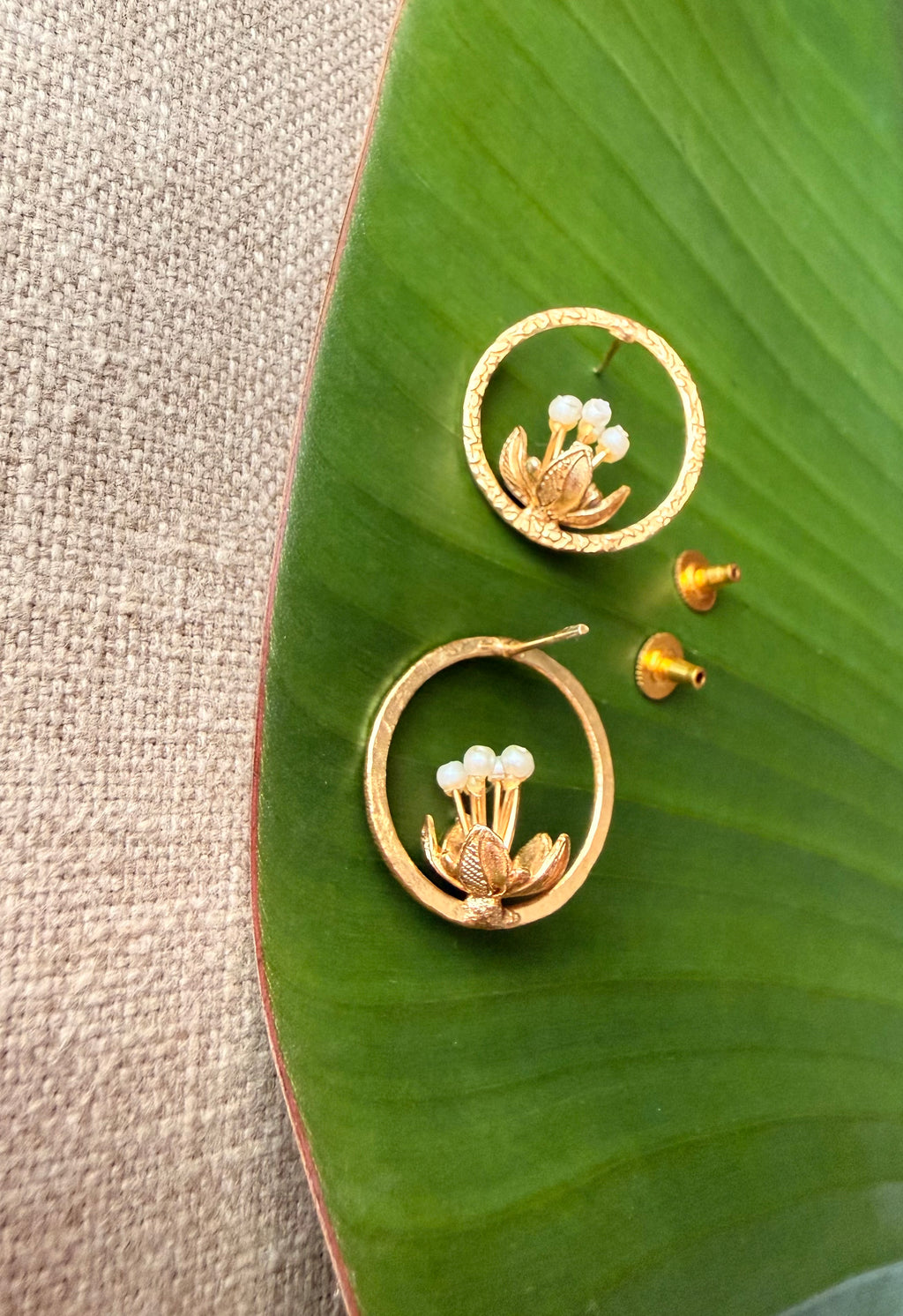 Detailed flat-lay view of the Tagar Studs displaying the earring posts and butterfly backs alongside the pearl-center floral design.