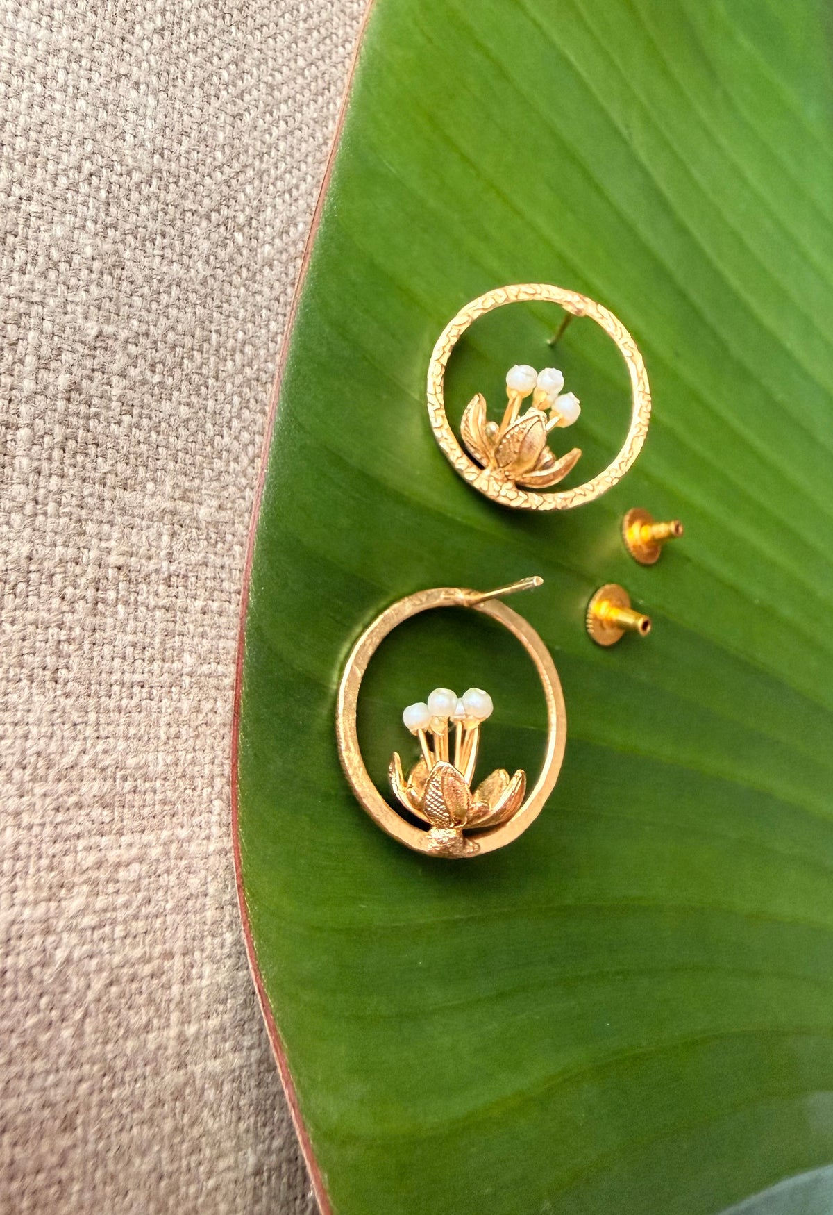 Detailed flat-lay view of the Tagar Studs displaying the earring posts and butterfly backs alongside the pearl-center floral design.