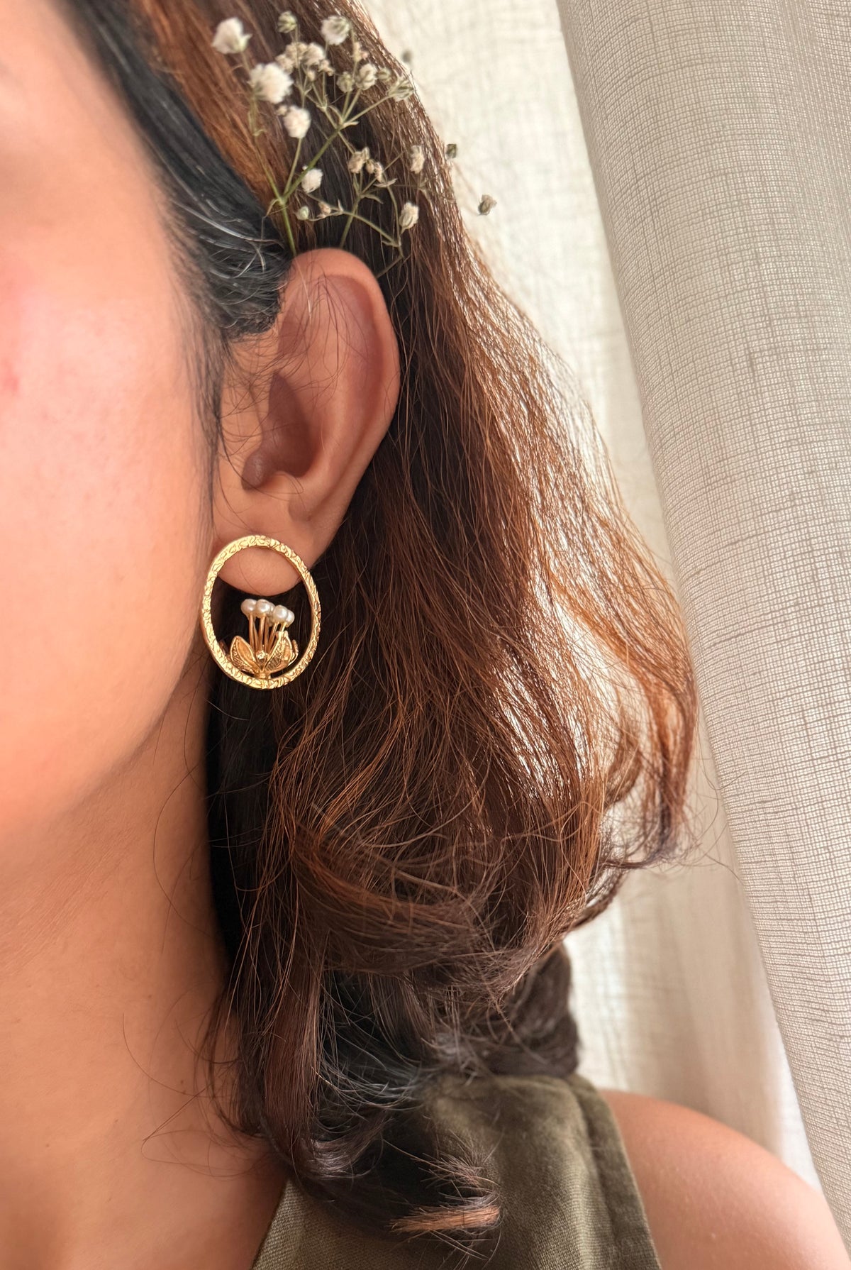 Close-up shot of a model wearing the Tagar Studs against a neutral linen background, highlighting how the earring frames the jawline.