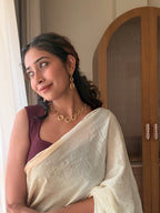 Woman in a white saree and maroon blouse looking out a window, wearing Valaya Danglers with the Valaya Necklace