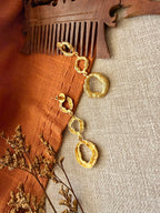 Valaya Danglers flat lay from another angle on rust cloth and linen with a carved wooden comb and dried flowers, showing the post and three graduated rings