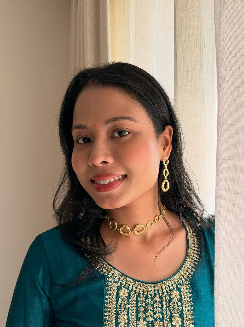 Woman in a teal embroidered kurta wearing the Valaya Necklace and Valaya Danglers, smiling