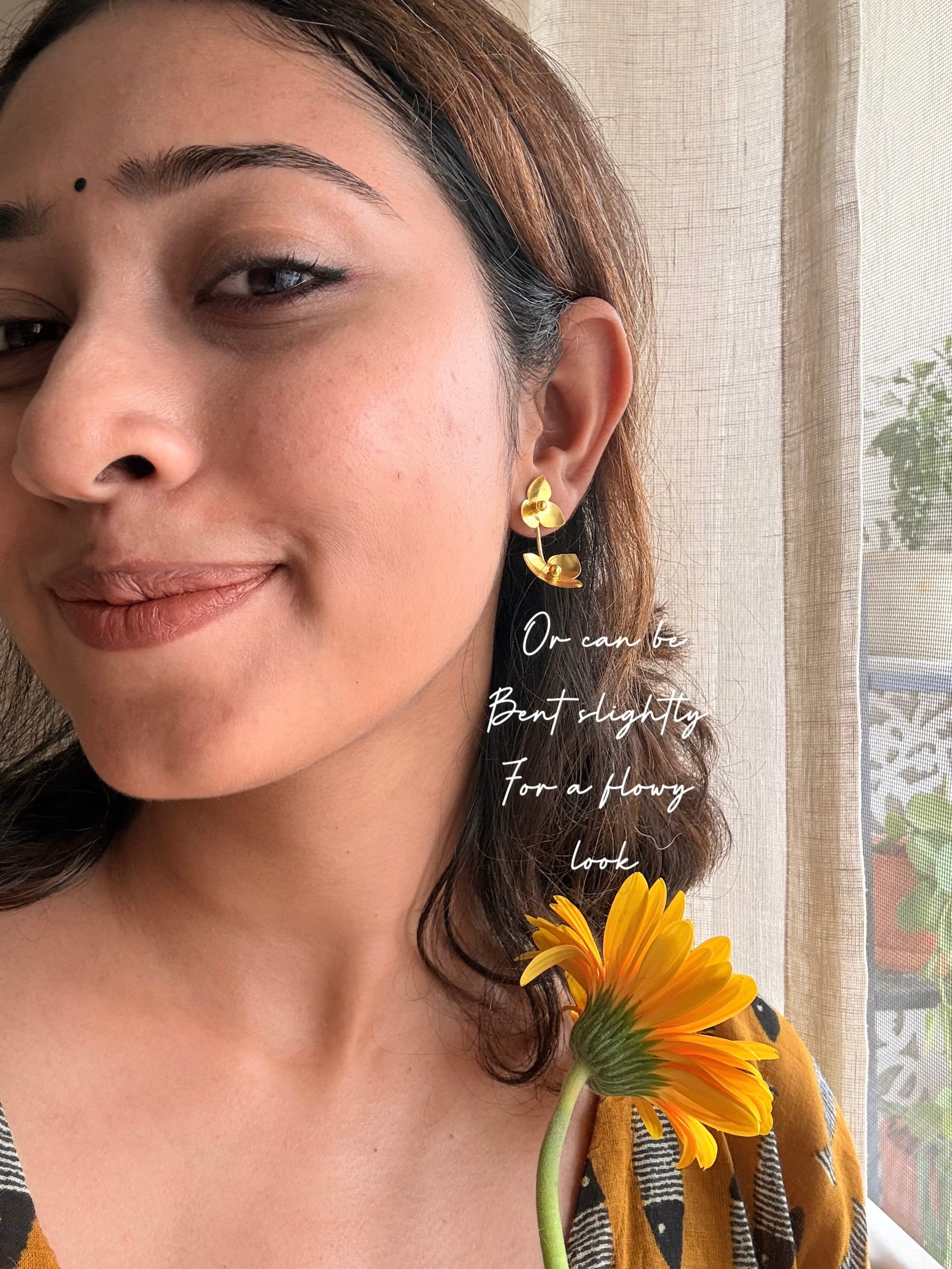 Woman wearing juhi floral earrings with a neutral background, with text- or it can bent slightly for a flowy look